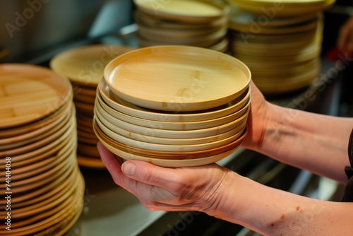 bamboo plates and bowls stacked in hands in a kitchensetting photo