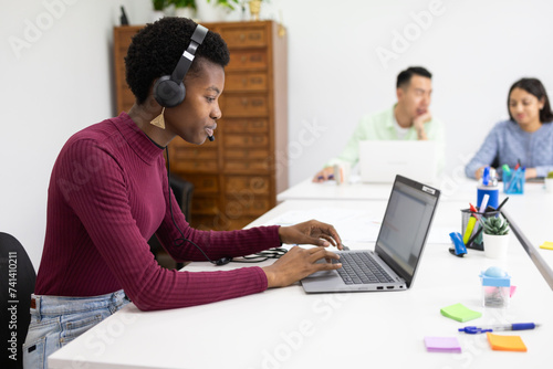 African woman focuses on work in a collaborative office space photo