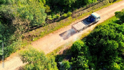 Aerial view of a 4x4 vehicle on a dirt road in a dense green forest.