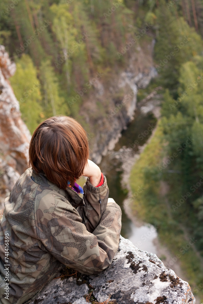 a woman is sitting on a rock overlooking a river