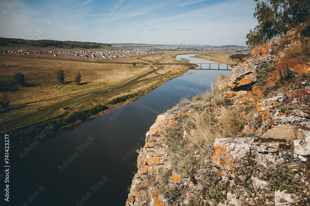 a view of a river from a cliff with a bridge in the distance