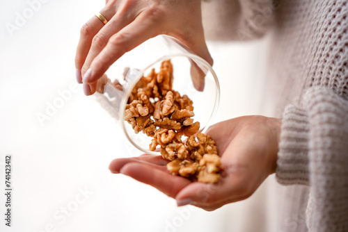 Walnuts spilling from jar in woman's hand. Walnuts in woman hands