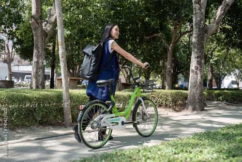 Asian businesswoman rides a bicycle to work in the office to reduce air pollution and protect the environment.