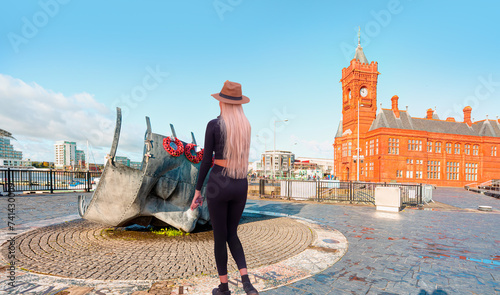 A beautiful blonde woman with a stylish hat wearing black tight trousers walking on the street  - Merchant Seafarers’ War Memorial - Cardiff, Wales