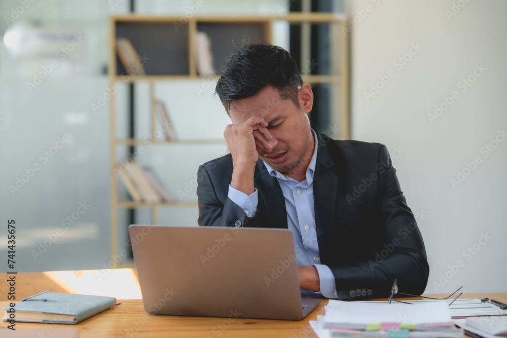 Asian businessman feeling stressed and tired at workplace. Work stress and mental health concept. Asian businessman feeling stressed and tired at workplace. Work stress and mental health concept.