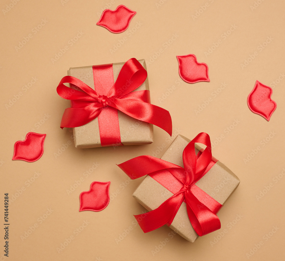 Gift box with red satin ribbon and bow on a brown background. Holiday background.