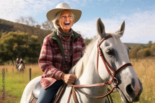 Senior woman riding a horse in the countryside, she is laughing and looking at camera