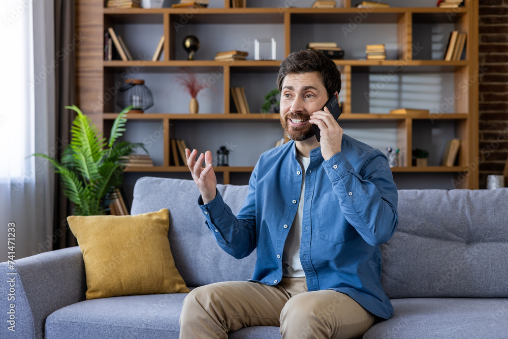 Happy man talking on smartphone at home, comfortable casual lifestyle concept