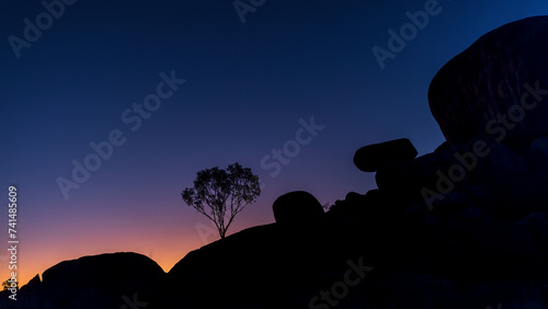 Devil's marbles, silhouette of a tree against the night sky, Australia photo