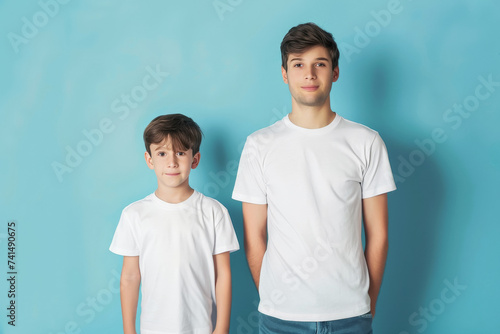 Pareja de hermanos caucásicos de diferentes edades  posando juntos con camisetas blancas, sobre fondo azul photo