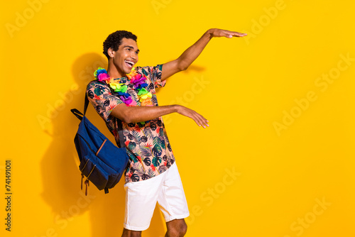 Photo of boogie woogie party guy t shirt has chill vibe dance in hawaiian necklace and backpack isolated over yellow color background photo