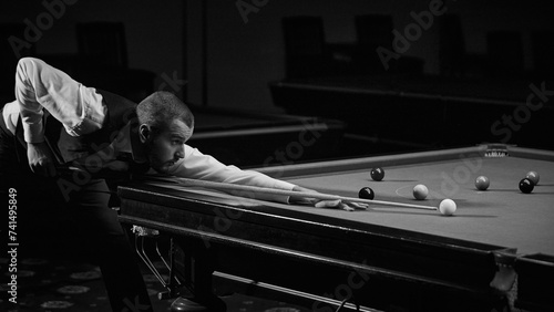 Stylishly dressed guy confidently playing in snooker game. Advertisement image of trendy billiards lounge or bar. Black and white. Concept of billiards sport, gambling, hobby, leisure, game photo