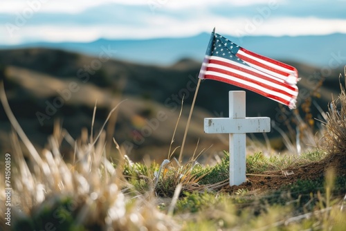 White cross in the grass on a hill with United States flag, Memorial Day holiday.