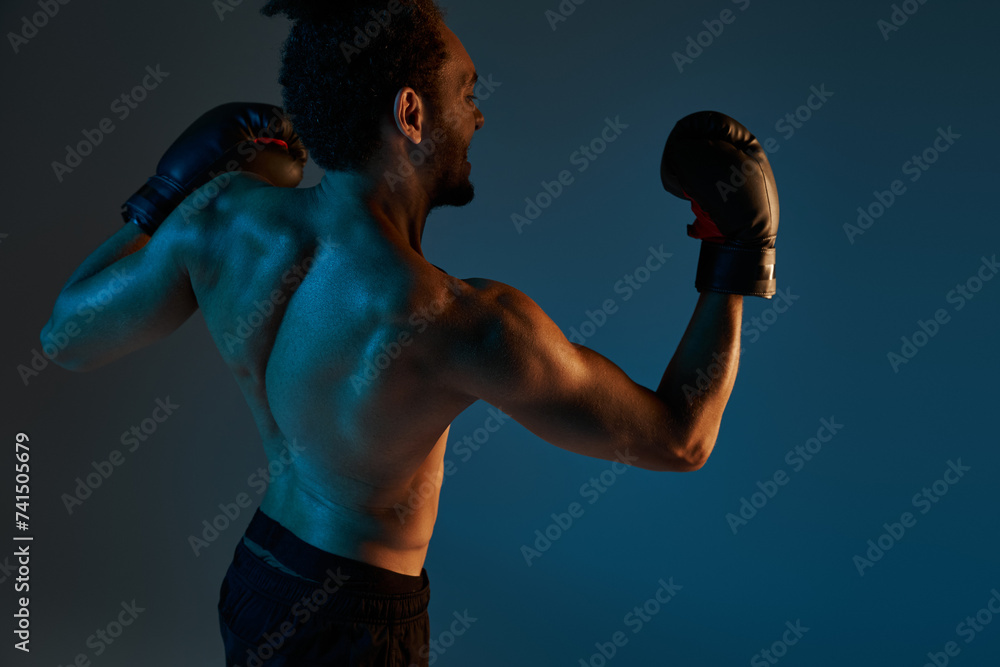 emotional handsome african american man in black shorts and boxing gloves training actively in gym