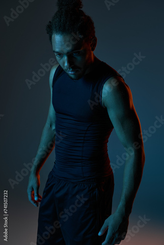 handsome african american man in sportwear posing actively on dark backdrop surrounded by light © LIGHTFIELD STUDIOS