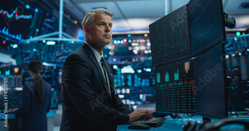 Portrait of Middle-Aged Stock Exchange Broker Working on Computer with Multi-Screen Workstation with Real-Time Stocks, Commodities, Exchange Market Charts. Professional Investment Agent in Office