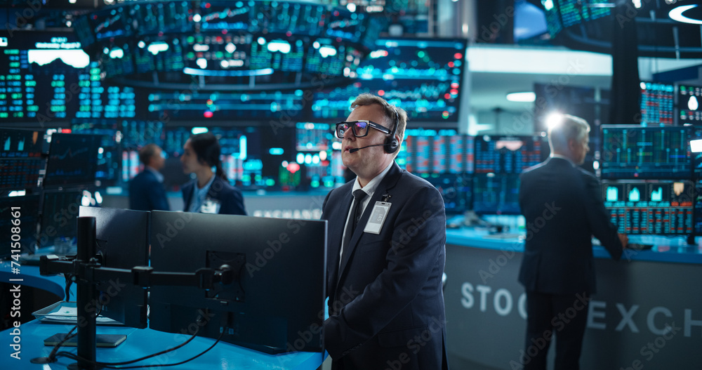 Fototapeta premium Portrait of Professional Middle Aged Trader Working on a Stock Exchange. Stylish Adult Man Communicating Buy and Sell Orders on a Call and Showing Hand Signals to an Arbitrage Broker