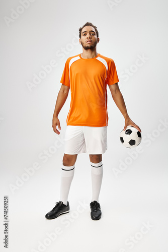 Fototapeta Naklejka Na Ścianę i Meble -  good looking young african american man in sportwear posing with football on gray background
