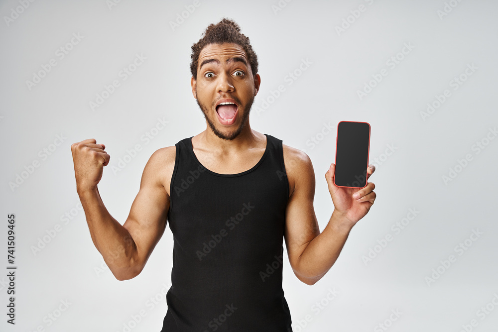 cheerful african american man in sportwear holding smartphone and looking at camera, online betting cheerful african american man in sportwear holding smartphone and looking at camera, online betting