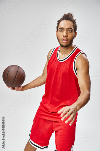 attractive athletic african american man in vivid sportwear holding basketball and looking at camera