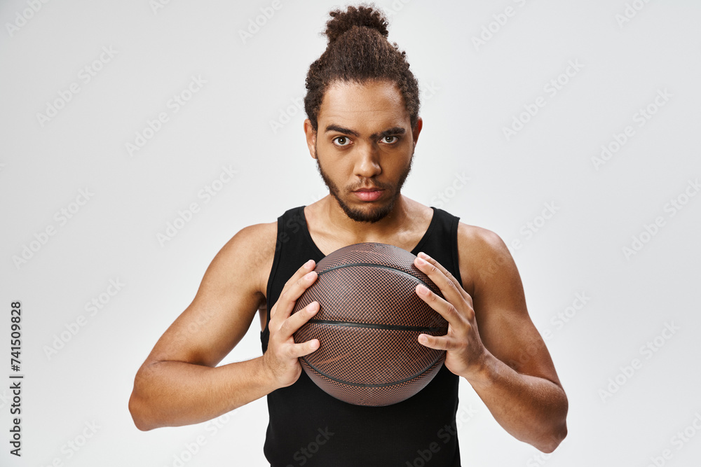 attractive athletic african american man in sportwear holding basketball and looking at camera