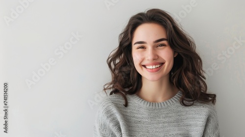 Young beautiful brunette girl smiling on a white background. There is space for text. The concept of minimalism and bright emotions. Suitable for advertising dentistry, cosmetology or stable quality l