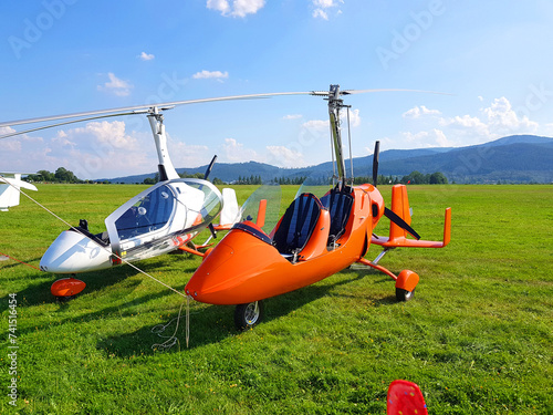 Two autogyro gyrocopter. Small plane in the meadow against the background of the mountains