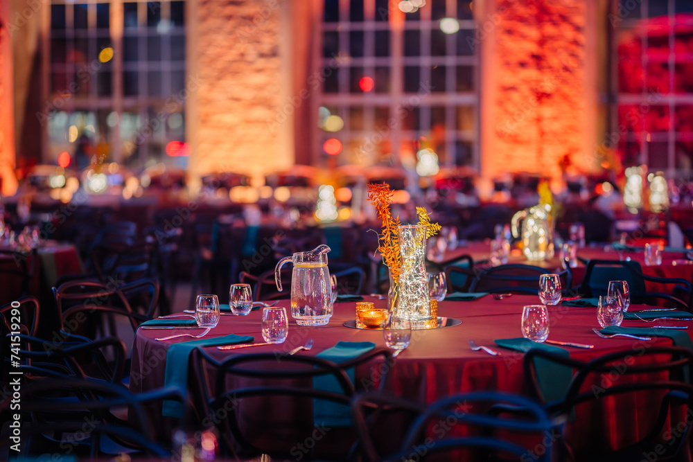 © Raivo - Riga, Latvia - February 16, 2024 - a festive event setting with tables, glowing centerpieces, and illuminated brick walls.