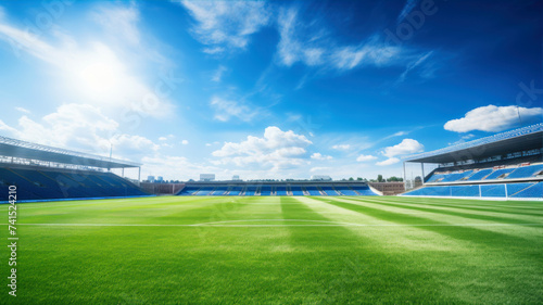 Empty soccer stadium with green grass and blue sky in sunny day.