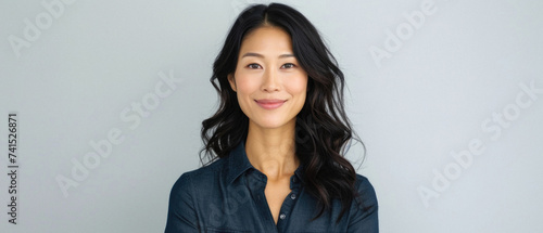 Beautiful confident Asian woman of middle age posing for portrait. Pretty mature adult lady model from Asia looking at camera smiling on background advertising products and services. Close up face . photo