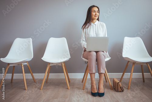 Business people waiting for job interview,Stressful people waiting for job interview. Tired of waiting. Bsinesswoman holding paper and looking away while sitting on chair against grey background