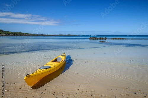 yellow kayak on sandy beach, clear water, blue sky above