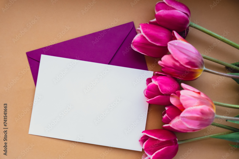 Empty white envelope copy space for your text or design with beautiful pink tulip bouquet on beige background. Template mock up for holiday spring greeting card. Top view Flat lay blank paper Feminine Empty white envelope copy space for your text or design with beautiful pink tulip bouquet on beige background. Template mock up for holiday spring greeting card. Top view Flat lay blank paper Feminine