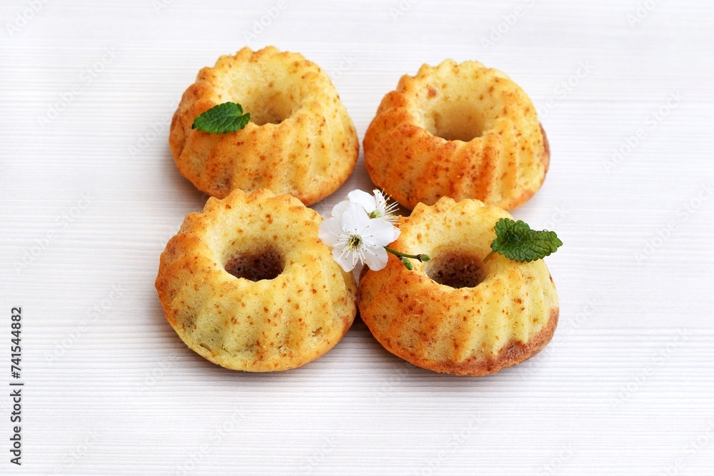 Mini bundt cakes decorated with lemon balm leaves and spring blooming twig, light background Mini bundt cakes decorated with lemon balm leaves and spring blooming twig, light background