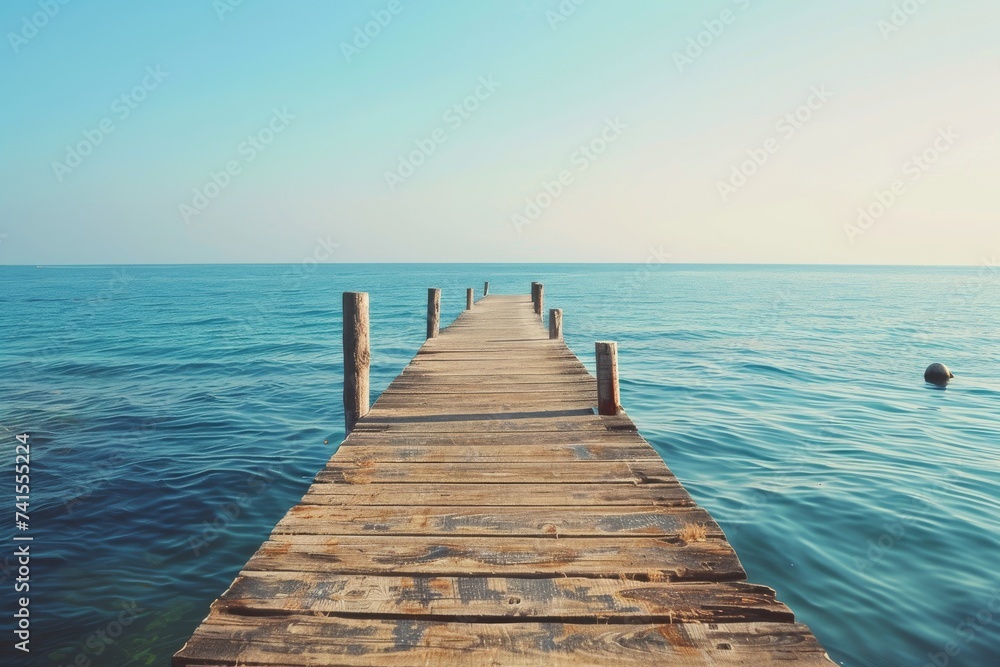 The rustic wooden dock stretched out over the crystal clear water, connecting the tranquil sky to the serene lake, creating a picturesque boardwalk for beachgoers to bask in the beauty of the ocean