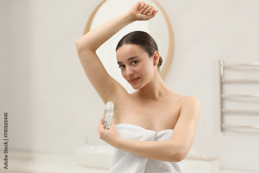 Beautiful young woman applying deodorant in bathroom Beautiful young woman applying deodorant in bathroom