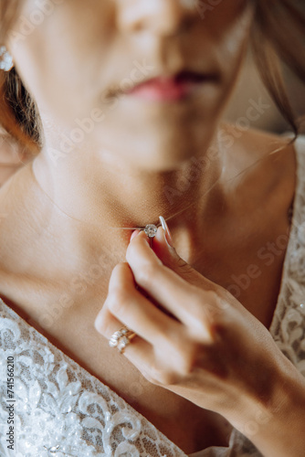 The bride touches the pendant on her neck with her fingers. Preparation for the wedding. Wedding celebration.