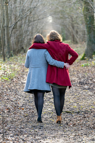 Couple de femmes photographiées de dos marchant dans la forêt