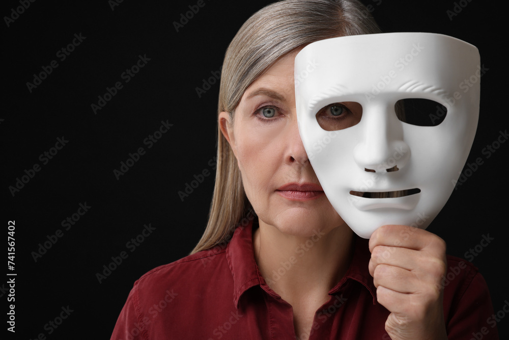 Multiple personality concept. Woman with mask on black background Multiple personality concept. Woman with mask on black background