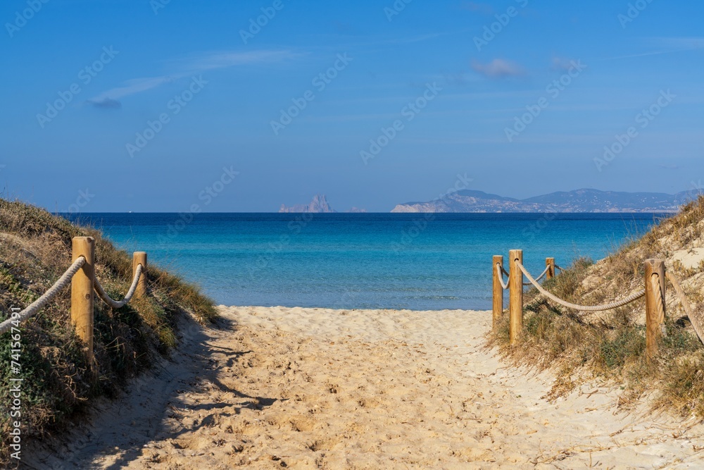 beach access leads to Ses Illetes beach on Formentera with a view of Ibiza and Es Vedra in the background