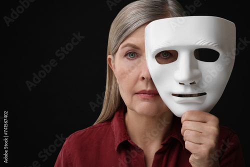 Multiple personality concept. Woman with mask on black background