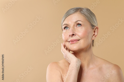 Beautiful mature woman with healthy skin on beige background  space for text
