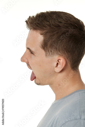 young man shows her toung, feels disgust on white background.