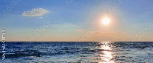 Colorful sunset with large sun under the sea waves.