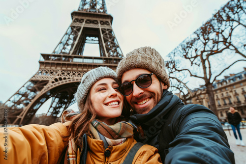 Smiling couple taking a selfie with the Eiffel Tower in the background on a clear day in Paris.