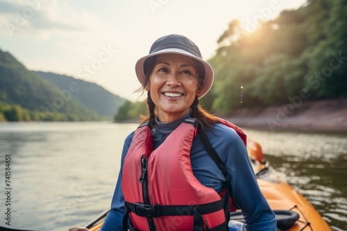 Happy woman paddling a kayak on a lake in the mountains © Nerea