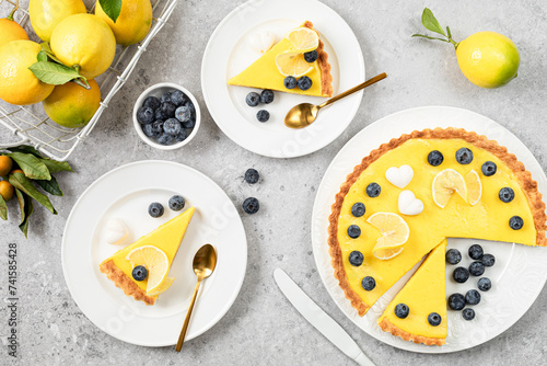 Traditional French lemon pie with blueberries on a white stone background.