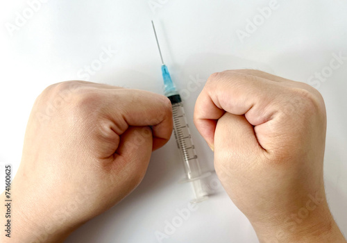 Syringe for injection with clenched hands potraying fear to needle, Trypanophobia. photography isolated on plain white studio background.