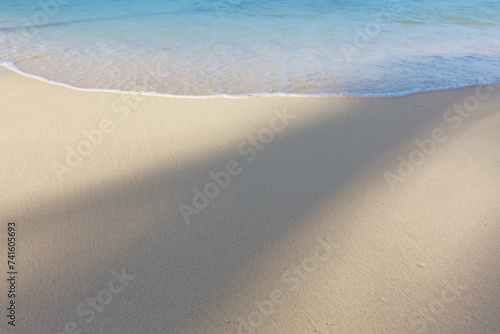 Travel background with soft wave of blue ocean on sandy beach.