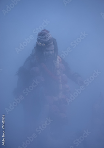 Fototapeta Naklejka Na Ścianę i Meble -  Masan Holi, Portrait of an male artist act as lord shiv with dry ash on face and body also in air while celebrating the holi festival as tradition at Harishchandra ghat in varanasi, India.